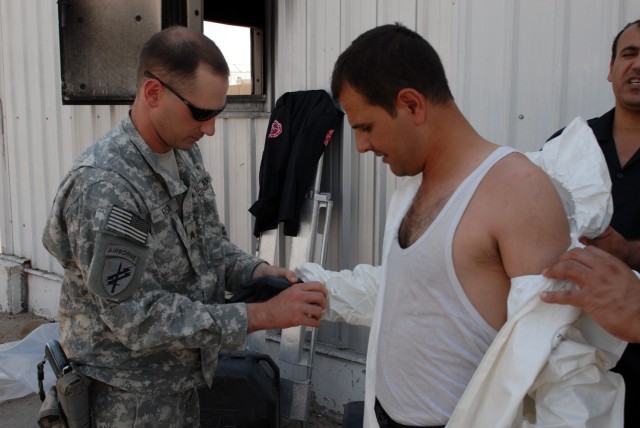 BAGHDAD - Sgt. Michael Kuca of Fairbanks, Alaska, a civil affairs specialist assigned to the 425th Civil Affairs Battalion, 364th Civil Affairs Brigade, 1st Cavalry Division, helps an Iraqi firefighter egress from a hazardous material suit at the...