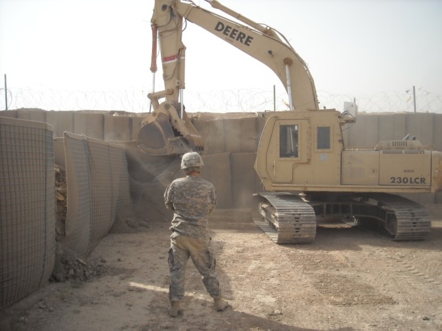 BAGHDAD - San Antonio native Sgt. Marcos Delgado, 277th Engineer Company, 46th Engineer Combat Battalion (Heavy), 225th Engineer Brigade, guides the excavator operator, Spc. Dennis Erickson, a native of Waco, Texas, during the reconstruction of a sma...