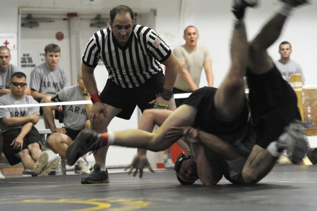 U.S. Army Staff Sgt. Joshua Greenwood, assigned to Headquarters and Headquarters Company, 1st Battalion, 67th Armor Regiment, attached to 3rd Heavy Brigade Combat Team, 1st Cavalry Division, keeps a close watch as he referees a wrestling match...