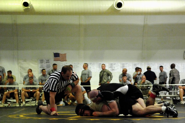 U.S. Army Staff Sgt. Joshua Greenwood (left), with Headquarters and Headquarters Company, 1st Battalion, 67th Armor Regiment, attached to 3rd Heavy Brigade Combat Team, 1st Cavalry Division, referees a match during a wrestling tournament at...