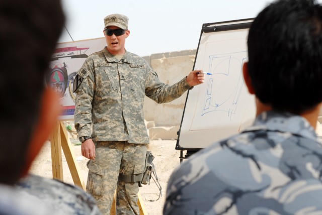 BAGHDAD - Iraq National Police watch attentively as Sgt. Aaron Eckert, a cavalry scout from Spokane, Wash., assigned to 1st Squadron, 7th Cavalry Regiment, 1st Brigade Combat Team, 1st Cavalry Division, explains a diagram on how to conduct caches...