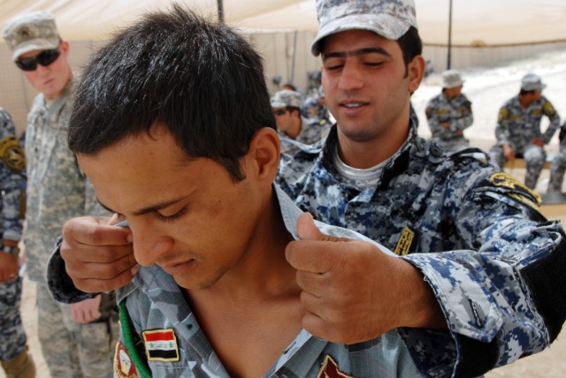 BAGHDAD - An Iraqi National Police officer searches a fellow police officer during a training exercise for Wolf Academy as Sgt. Aaron Eckert (left background), a cavalry scout and a native of Spokane, Wash., assigned to 1st Squadron, 7th Cavalry...