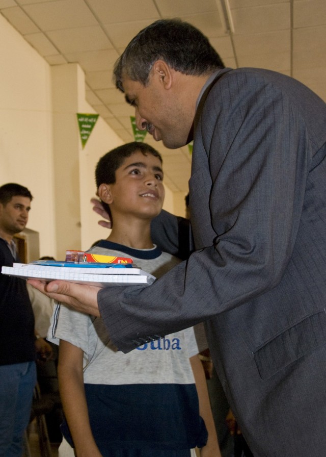 BAGHDAD -Shaker Fiza, a local government leader in Abu Ghraib, gives school supplies donated by supporters of the 2nd Battalion, 112th Infantry Regiment, "Paxton Rangers," 2nd Heavy Brigade Combat Team, 1st Infantry Division, Multi-National Division ...