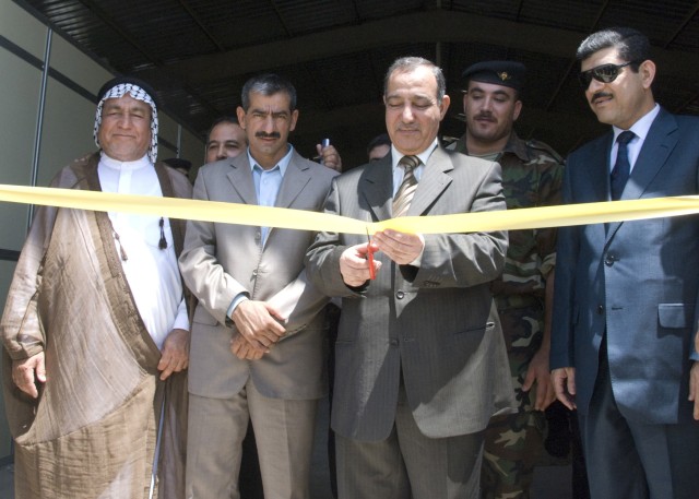 BAGHDAD - Standing among government and community leaders from Abu Ghraib, Dr. Nihad Abbas Shihad al-Juburi (center), the Baghdad deputy minister of education, cuts the ceremonial ribbon at the conclusion of a ceremony honoring the opening of the Abu...