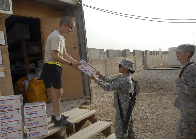 BAGHDAD - Spc. Jody Emerson (left), from Marshall, Texas, a mail room clerk serving with the Brigade Special Troops Battalion, 2nd Heavy Brigade Combat Team, 1st Infantry Division, Multi-National Division-Baghdad, hands a care package to Spc....