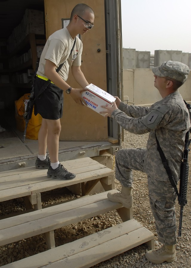 BAGHDAD - Spc. Jody Emerson (left), a native of Marshall, Texas, a mail room clerk serving with the Brigade Special Troops Battalion, 2nd Heavy Brigade Combat Team, 1st Infantry Division, Multi-National Division - Baghdad, hands a care package to...