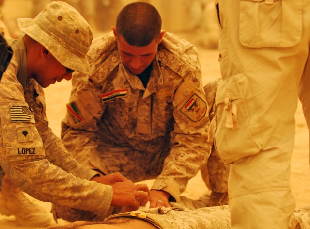 BAGHDAD - Spc. Cesar Lopez, of Miami, Fl. gives pointers to an Iraqi Army Soldier appling a pressure dressing on a simulated wound during a training exercise in the midst of a sandstorm, July 29, at Combat Outpost Carver Iraq, located in Salman Pak, ...