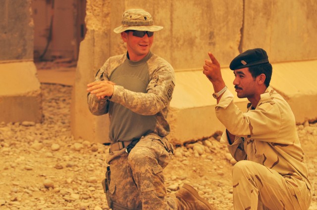 BAGHDAD - A U.S. Paratrooper assigned to Company A, 1st Battalion, 505th Parachute Infantry Regiment, 3rd Brigade Combat Team, 82nd Airborne Division, Multi-National Division - Baghdad, instructs an Iraqi Soldier on how to guard the rear of a squad f...