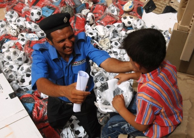 CAMP TAJI, Iraq - An Iraqi Policeman gives a soccer ball to a young boy in Tarmiyah, north of Camp Taji, on 29 July.  Soldiers with the 56th Stryker Brigade Combat Team, Multi-National Division - Baghdad helped coordinate Operation Future Hero,...