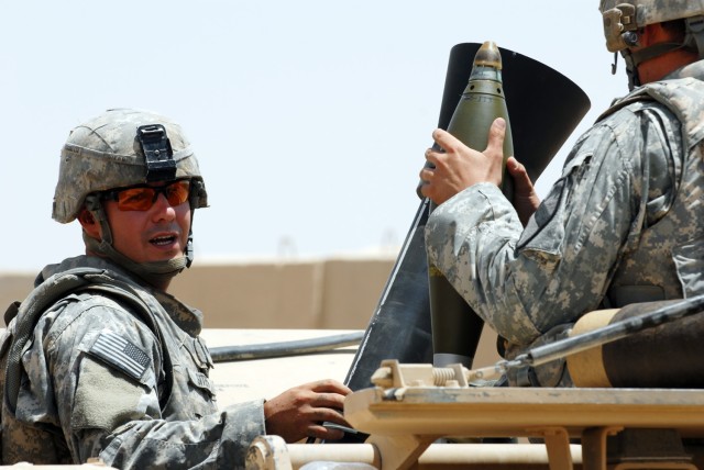 BAGHDAD - Spc. Randy Sites (left), from Rising Sun, Md., communicates with Spc. Gordon Brooks from Tucson, Ariz., as they prepare to fire their first mortar since arriving in Iraq six months ago at Joint Security Station Istaqlaal, here. Both Soldier...