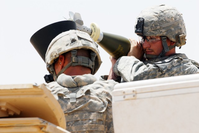 BAGHDAD - Tucson, Ariz. Spc. Gordon Brooks (right), gets ready to drop a high-explosive (HE) round into a mortar tube as Spc. Randy Sites (left), from Rising Sun, Md., prepares to duck down during a fire mission exercise at Joint Security Station Ist...
