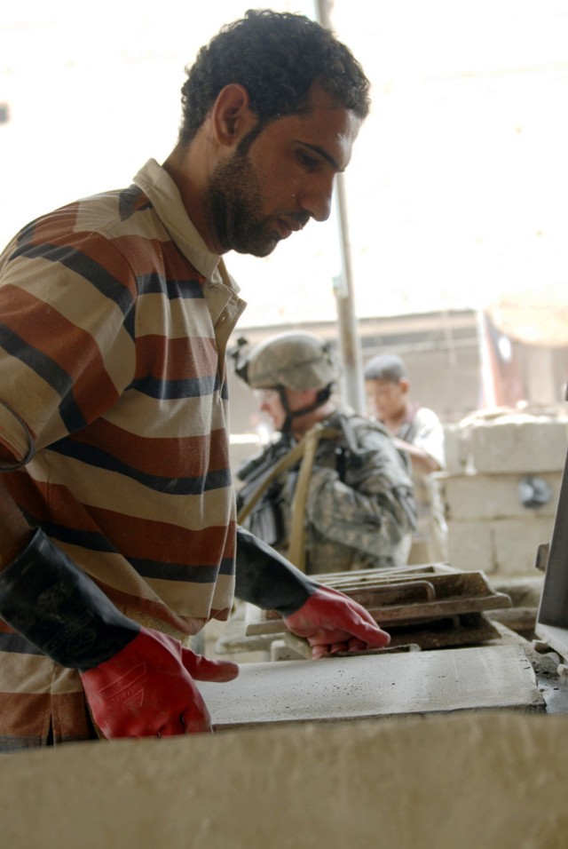 BAGHDAD - An Iraqi tile-maker puts the finishing touches on a piece of tile as a Soldier from 1st Squadron, 7th Cavalry Regiment, 1st Brigade Combat Team, 1st Cav. Division, walks through the factory in Boob al-Sham, here, July 30. The Soldiers joine...
