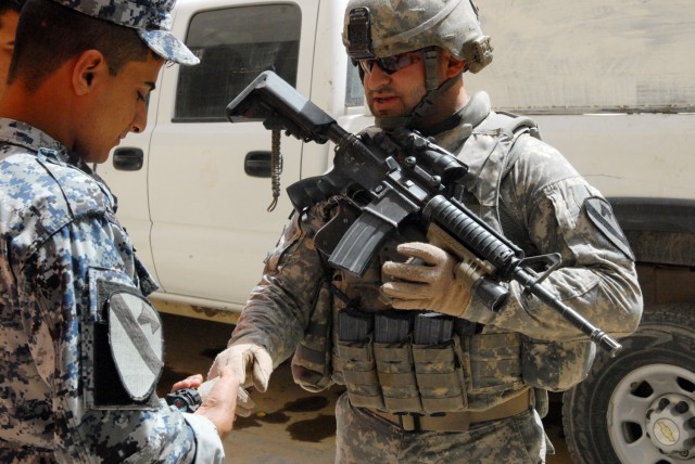 BAGHDAD - Staff Sgt. Robert Mosqueda, a cavalry scout section leader from Mission, Texas, assigned to 1st Squadron, 7th Cavalry Regiment, 1st Brigade Combat Team, 1st Cavalry Division, talks shop with an Iraqi Federal Police officer before heading to...