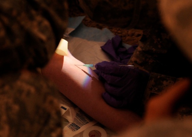 BAGHDAD - Staff Sgt. Joseph Montague, Company B, 230th Brigade Support Battalion, 30th Heavy Brigade Combat Team, prepares to start intravenous fluids for Jacksonville, N.C. native Sgt. Stephanie Brasington, Company C, 230th BSB, as part of a...