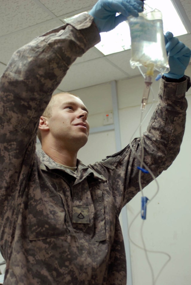 TAJI, Iraq - Houston, Texas native Pfc. Andrew Britt, medic for Co. B, 1st Battalion, 5th Cavalry Regiment, attached to 1st Brigade Combat Team, 1st Cavalry Division hangs a bag of saline with antibiotics in order to treat a Soldier with an infection...