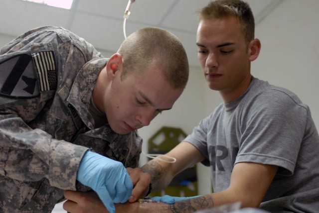 TAJI, Iraq - Houston, Texas native Pfc. Andrew Britt, medic for Co. B, 1st Battalion, 5th Cavalry Regiment, attached to 1st Brigade Combat Team, 1st Cavalry Division connects the IV line for Dimondale, Mich. native Spc. Brandon Rich, a mechanic for C...