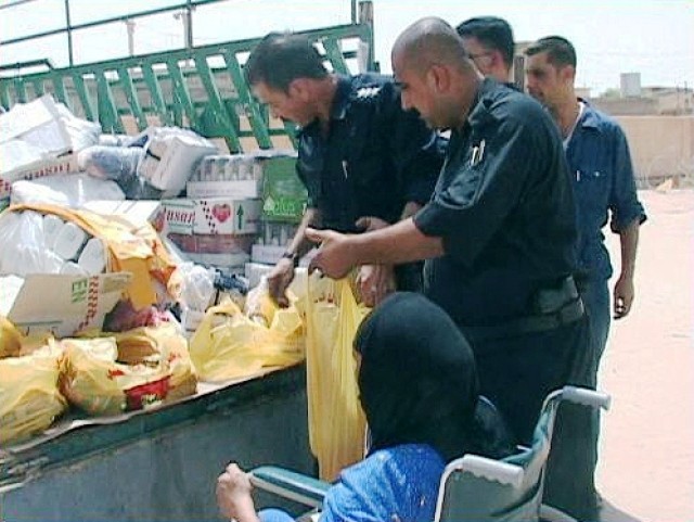 Iraqi Police from the Aruba sub-district police station, in Kirkuk, Iraq, give a food bag to an elderly Iraqi woman during a humanitarian aid delivery July 27. The IP, with assistance from the U.S. Army, delivered food, toys, and school supplies to a...