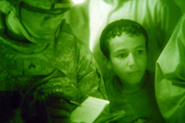 BAGHDAD - Cpl. Ivan Ibabao, a cavalry scout from Houston, assigned to 1st Squadron, 7th Cavalry Regiment, 1st Brigade Combat Team, 1st Cavalry Division, takes notes while talking to local community members as an Iraqi child looks on during a joint ni...