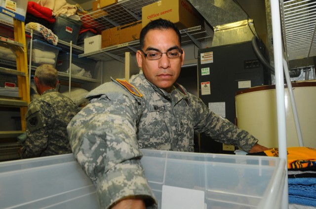 Army Staff Sgt, Frank Marquez, a student at the Signal Corps Regimental Non-Commissioned Officer Academy Detachment, Advanced Non-Commissioned Officer Course 009-02 (RC), reaches for more laundry to fold as he helps to reorganize linen storage at...