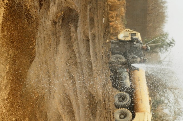 TAJI, Iraq - Pfc. Kenneth Gould (right), of San Antonio, Texas, uses water from the Tigris River to compact the dirt engineers from the 277th Engineer Company, 46th Engineer Battalion, 225th Engineer Brigade moved as Command Sgt. Maj. Joe Major,...
