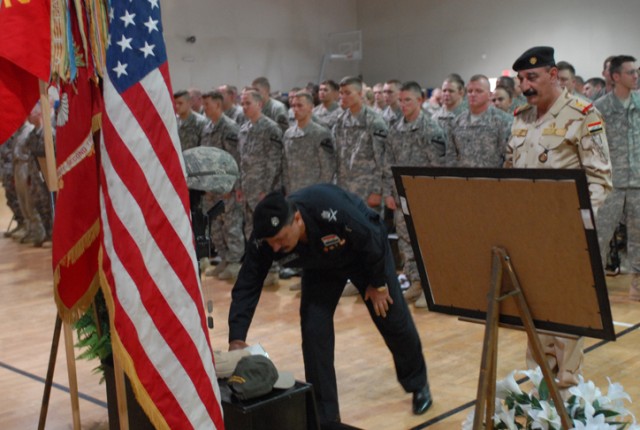 Maj. Gen. Jamal, the Kirkuk province police chief, places an item on Sgt. 1st Class Johnny Polk's memorial while Maj. Gen. Ameer, the commander of the 12th Iraqi Army Division, watches during a ceremony in Polk's honor on Forward Operating Base...
