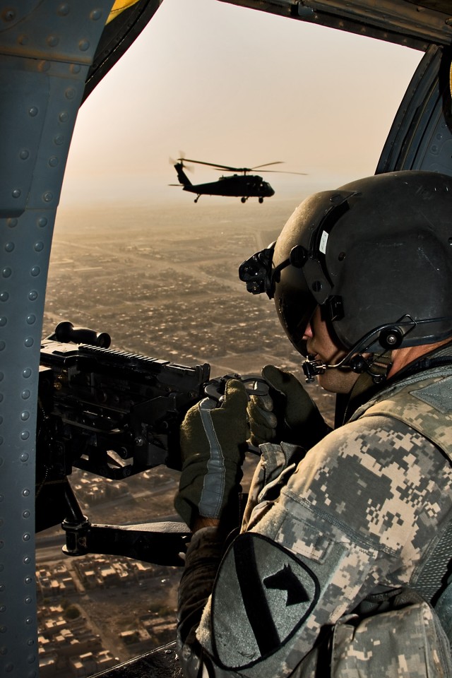 CAMP TAJI, Iraq-As another UH-60 Black Hawk rides the horizon, Spc. Kevin Hood, a Black Hawk crew chief in Company B, 3rd Battalion, 227th Aviation Regiment, 1st Air Cavalry Brigade, 1st Cavalry Division, Multi-National Division - Baghdad, mans a...