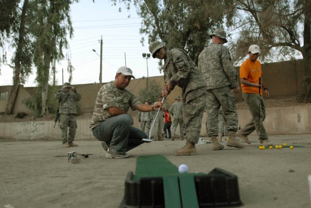 BAGHDAD - Tampa, Fla. Native, Mike Sposa (left), one of the "Fairways 2 Greens" golf pros, assists Rockingham, N.C. native Pvt. Anahi Padilla (right), human resource specialist assigned to Headquarters and Headquarters Troop, 1st Brigade Combat...