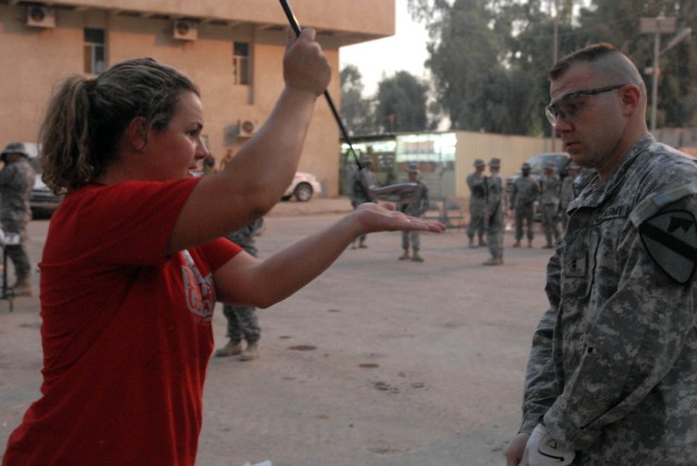 BAGHDAD - Phoenix native, Becky Lucidi (left), a golf pro with the "Fairways 2 Greens" Golf Tour, demonstrates how to properly use a pitching wedge to Rio Rancho, N.M. native, Chief Warrant Officer Michael McMurray, the electronic warfare officer...