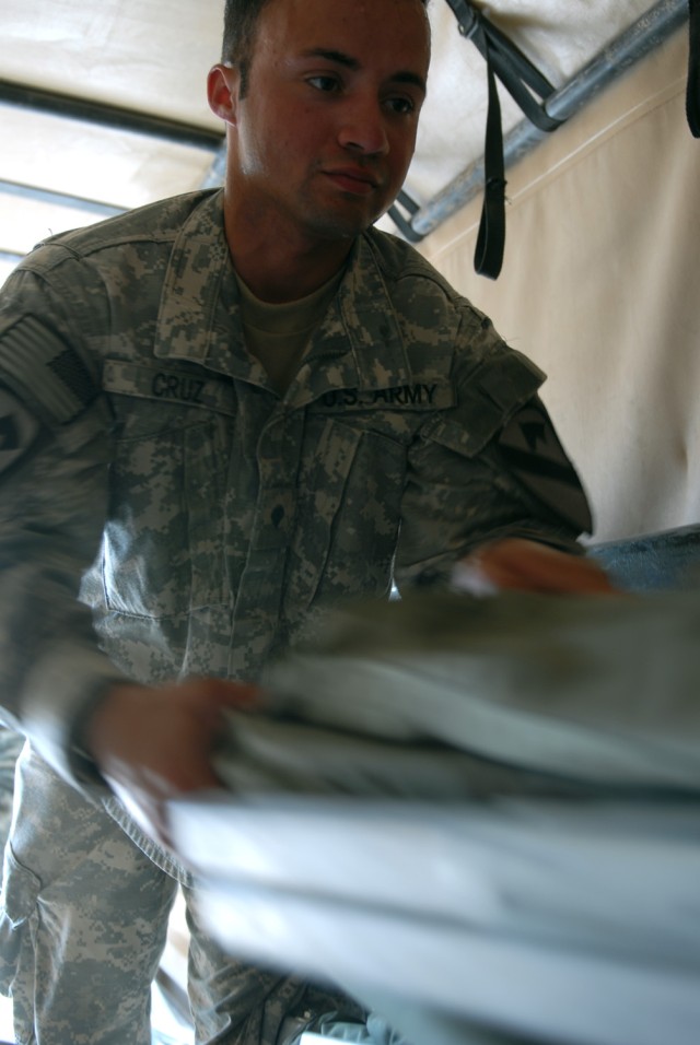 CAMP TAJI, Iraq - Fort Myers, Fla. native, Spc. Ezequiel Cruz, a fire direction control specialist assigned to Battery A, 1st Battalion, 82nd Field Artillery Regiment, 1st Brigade Combat Team, 1st Cavalry Division, removes gear from a truck as...