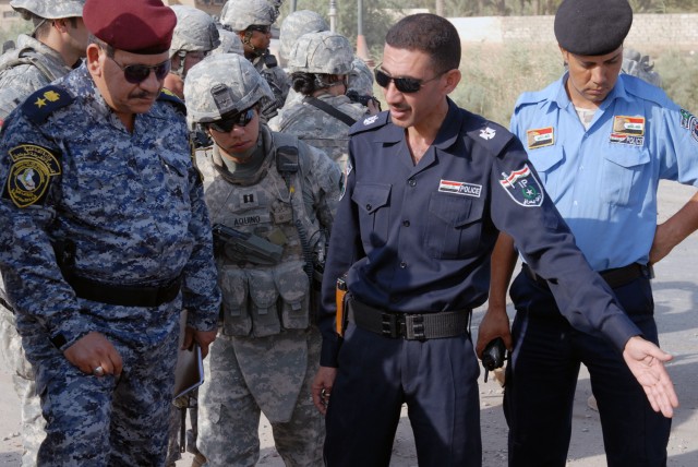 CAMP TAJI, Iraq - Lt. Col. Majid Hentan (left), commander of the al-Wenda Battalion., 6th Brigade, 22nd Federal Police Division, and Capt. Alex Aquino (center), from Little Rock, Ark., listen closely as Maj. Thamir Jabbar Abid (right), the...