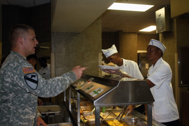 Food service Soldiers, assigned to the 4th Brigade Combat Team, 1st Cavalry Division "Long Knives," serve their first meal at the Operation Iraqi Freedom dining facility after their grand opening ceremony Aug. 27. The OIF dining facility feeds...