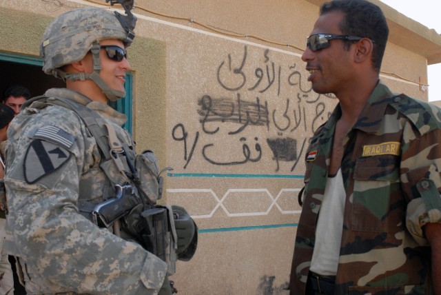 CAMP TAJI, Iraq - Austin, Texas native, Pfc. Zachary Sherman (left), a tanker assigned to the 1st "Black Knight" Battalion, 5th Cavalry Regiment attached to the 1st Brigade Combat Team, 1st Cavalry Division, jokes with a member of the Iraqi...