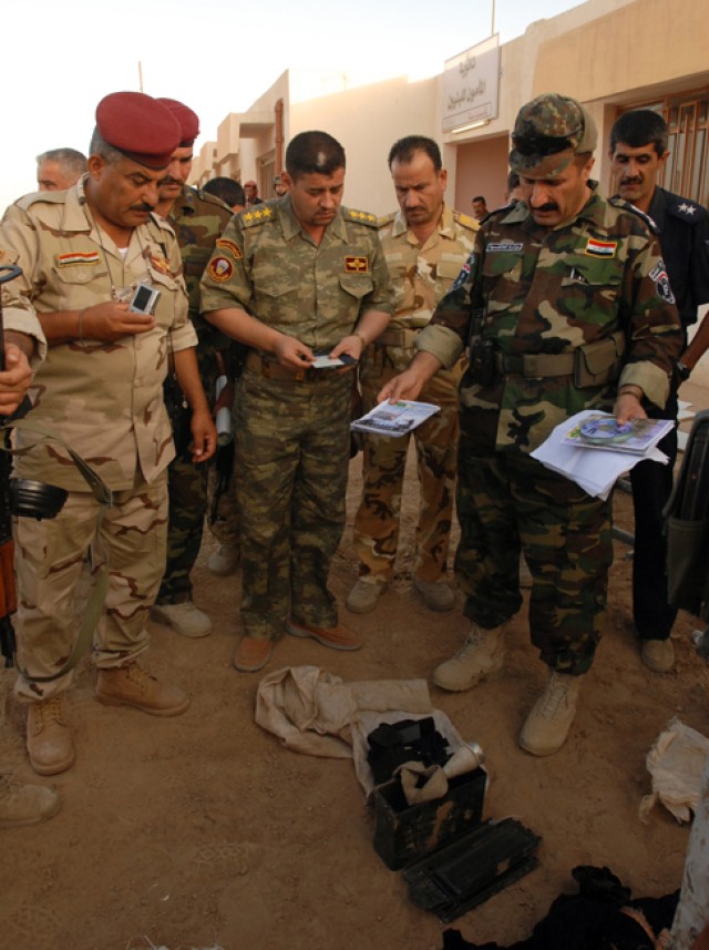 Brigadier General Sarhat (right), the outer city police chief for Kirkuk province, examines insurgent propaganda found during operation "Enforce the Law VI" in the Rashaad Valley in Kirkuk province, Iraq, Sept. 2. The operation was a joint venture...