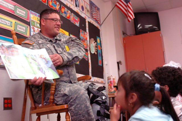 Pfc. Micheal Sparling shows photos as he reads to  Alexis Thompson and Eric Torres, pre-kindergarten students at Maxdale Elementary School in Killeen, Texas, Sept. 8.Four 'Greywolf' Soldiers spent two hours with pre-K students reading various childre...