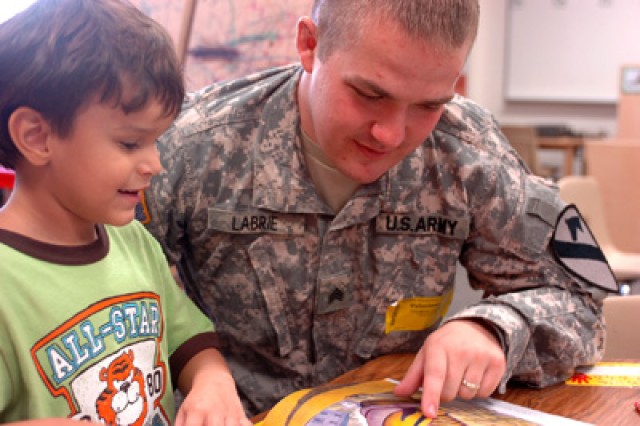 Sgt. Thomas Labrie reads along with 5-year-old Cris Luna a pre-kindergarten student, at Maxdale Elementary School in Killeen, Texas, during the schools literacy day Sept. 8. Four 'Greywolf' Soldiers spent two hours with pre-K students reading various...