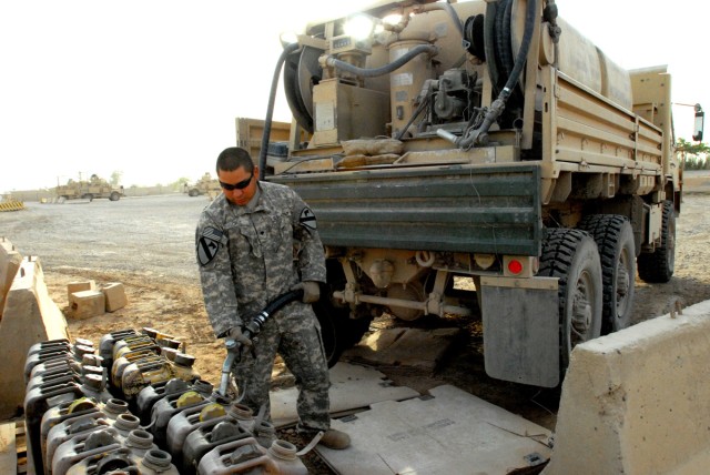 BAGHDAD - Spc. Israel Cruz, a fuel supply specialist, from Floresville, Texas, fills up five-gallon containers at a coordinated fuel point at Victory Base Complex, here, Sept. 8.  Some of the fuel points maintain generators for signal operations, mak...
