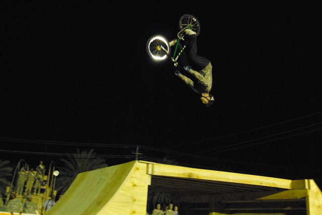 CAMP LIBERTY, Iraq - Donning an Army Combat Shirt, a gift from Soldiers, X-Games pro bike rider and gold medalist, Chad Kagy, does a back flip over a ramp as Soldiers sit on their Mine-Resistant Ambush-Protected vehicles to watch the "Bikes Over...