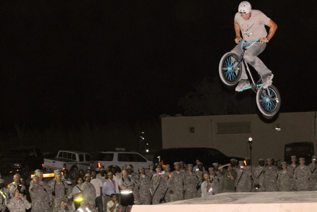 CAMP LIBERTY, Iraq - Dave Osato, an X-Games pro bike rider from Vancouver, British Columbia, jumps high in the air during an exhibition show as Soldiers crowd around the newly-created ramp park at Camp Liberty, here, Sept. 9. Seven X-Games...