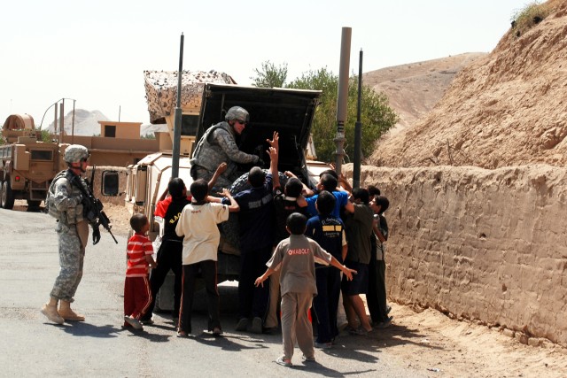 Soldiers of the 277th Aviation Support Battalion, 10th Combat Aviation Brigade's Quick Reaction Force hand out bottles of water to eager Iraqi children during an Aug. 4 mission to Al-Hasra. Over the past year, the troops have seen their missions...