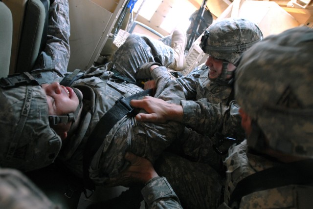 defense crewmember from Carson, Calif., gets help from Spc. Emery Bruner (far right), a signal support systems specialist from Kemp, Texas, and Spc. Dominick Bonds (near right), an Avenger system repairer from Chester, Va., as they tumble around in a...