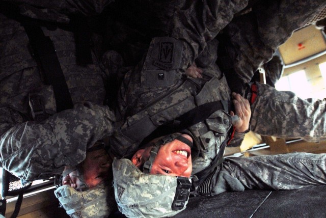 CAMP LIBERTY, Iraq - Spc. Rogelio Perez (left), an air and missile defense crewmember from Carson, Calif., receives a helping hand from Chester, Va., native Spc. Dominick Bonds (right), an Avenger system repairer, as they try to find their bearings i...