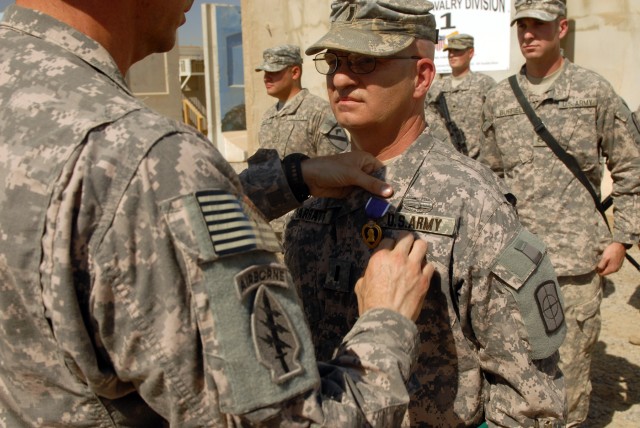 CAMP LIBERTY, Iraq - First Lt. Frank Sarratt, executive officer of the 211th Mobile Public Affairs Detachment, Division Special Troops Battalion, 1st Cavalry Division, receives a Purple Heart and the Combat Action Badge from DSTB commander, Lt. Col. ...