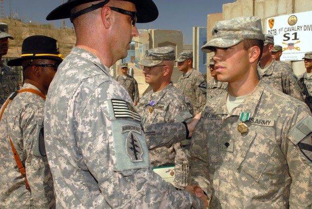 CAMP LIBERTY, Iraq - Spc. Jacob Belonga, an infantryman from Muskegon, Mich., receives an Army Commendation Medal with a "V" device for valor from Lt. Col. Matthew Karres, commander of Division Special Troops Battalion, 1st Cavalry Division, during a...