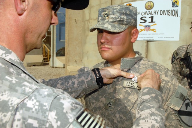 CAMP LIBERTY, Iraq - Pfc. Alan Antelo, a combat medic from Rolla, Mo., assigned to D Troop, Division Special Troops Battalion, 1st Cavalry Division, receives a combat medic badge during an awards ceremony here, Sept. 11. Lt. Col. Matthew Karres, comm...
