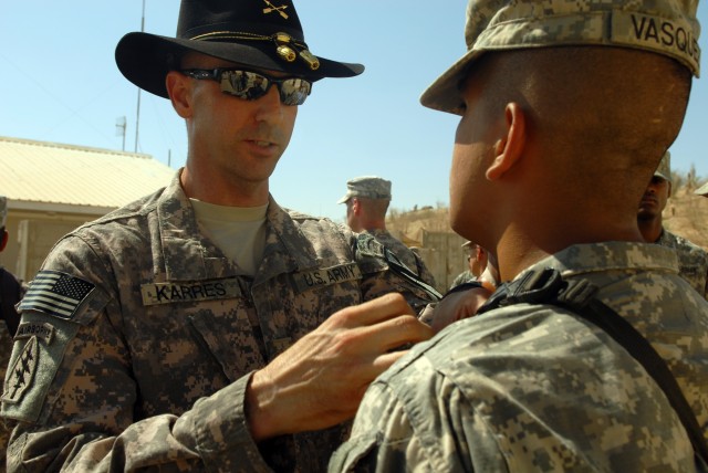 CAMP LIBERTY, Iraq - Lt. Col. Matthew Karres, commander of Division Special Troops Battalion, 1st Cavalry Division, pins a combat infantry badge on Pfc. Nathan Vasquez during an awards ceremony, here, Sept. 11. Fifteen "Maverick" Soldiers received co...