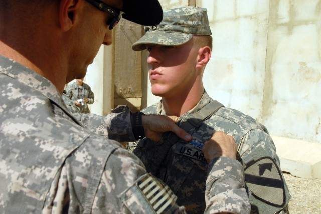CAMP LIBERTY, Iraq - Pfc. Casey Bass receives the combat infantry badge from Lt. Col. Matthew Karres, commander of the Division Special Troops Battalion, 1st Cavalry Division, during an awards ceremony, here, Sept. 11. Bass, an infantryman from Layto...