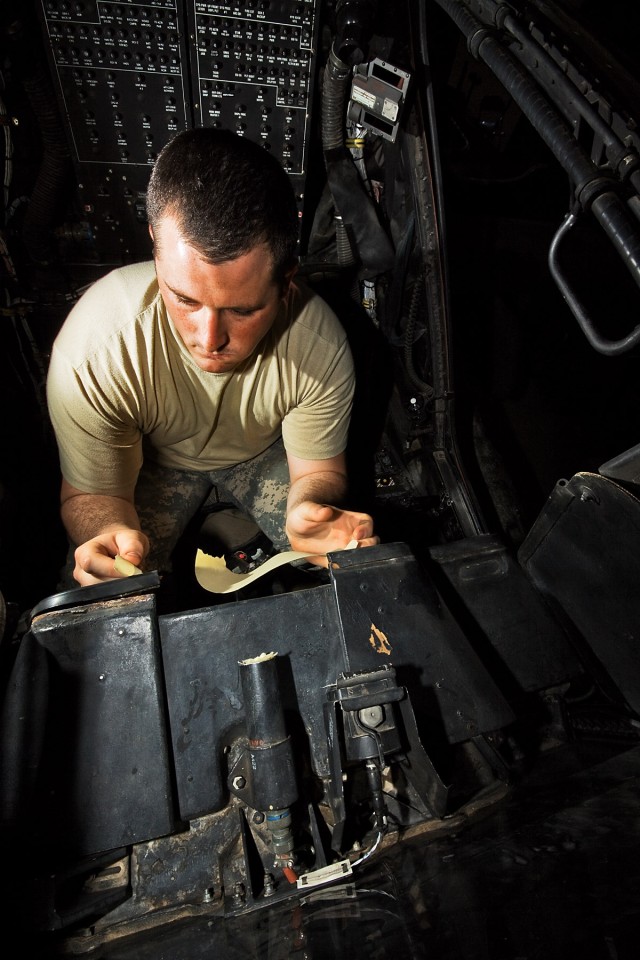 CAMP TAJI, Iraq-Taping off controls and buttons, Spc Zack Taylor, from Stockton, Calif., an AH-64D Apache attack helicopter mechanic in Company B, 615th Aviation Support Battalion, 1st Air Cavalry Brigade, 1st Cavalry Division, Multi-National...