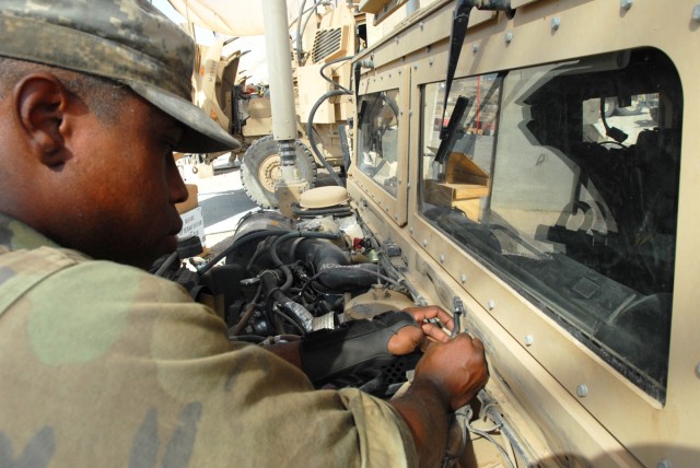 CAMP LIBERTY, Iraq - Spc. Edric Ashley, a light-wheel vehicle mechanic, from Houston, assigned to quality control and assurance, Division Special Troops Battalion, 1st Cavalry Division, demonstrates where a tube intersects a sprayer for fluid to...