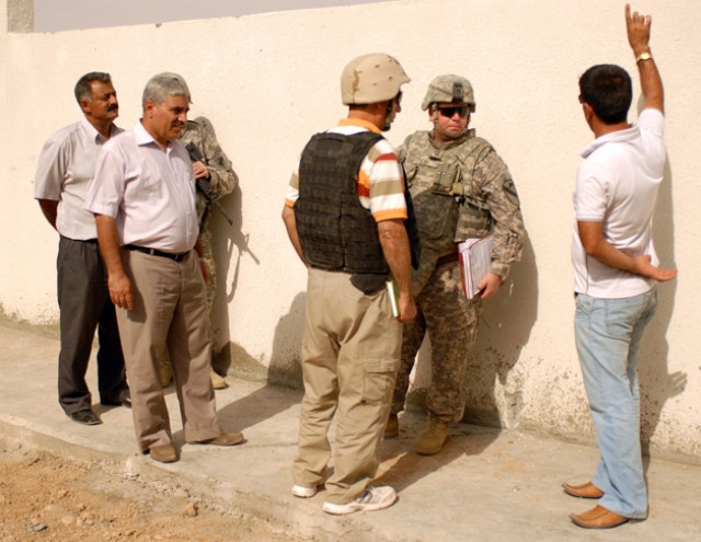 Sgt. 1st Class Carl Lay, a Carrollton, Texas, native and the essential services representative for 2nd Brigade Combat Team, 1st Cavalry Division, speaks with one of the engineers at the site of a new school being constructed in Chemin, Iraq, Sept. 8....