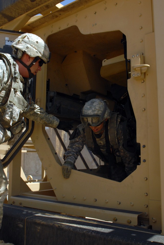 CAMP LIBERTY, Iraq - Staff Sgt. Robert Zulch, of Dickinson, Texas, helps Spc. Adam Stewart, of Mt. Pleasant, Iowa, climb out of the Mine-Resistant Ambush-Protected Vehicle Egress Training (MET) at Camp Liberty, here, Sept. 25. Zulch, an...